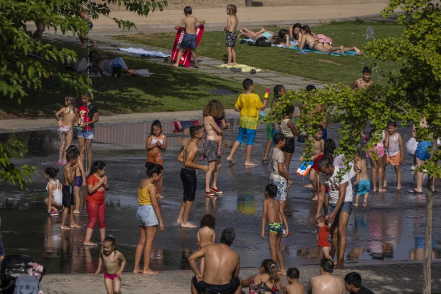 In Madrid kühlen sich Einwohner bei einem Brunnen in der Stadt ab.