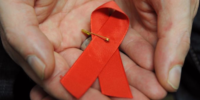 Ein mit dem HIV-Virus infizierter Mann mit einer roten Schleife als Symbol der Solidarität mit HIV-Positiven und Aids-Kranken. hiv