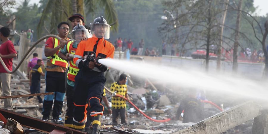 Einsatzkräfte der Feuerwehr löschen einen Brand in einem durch eine Explosion zerstörten Gebäude in Thailand. Foto: Kriya Tehtani/AP