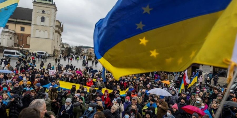 Demonstranten in Warschau schwenken die ukrainische Fahne