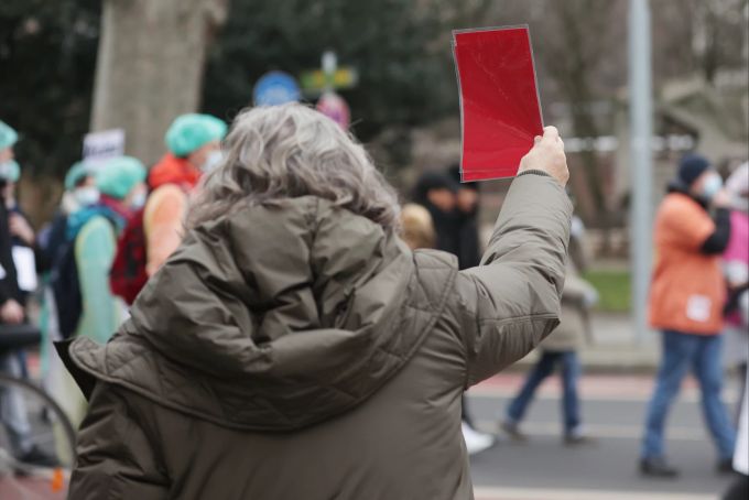 Eine Gegendemonstrantin zeigt Massnahmengegnern eine rote Karte. Demo