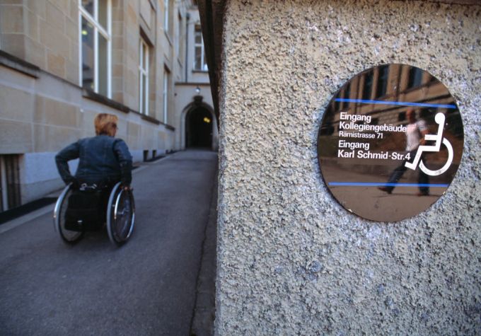 Eine Person im Rollstuhl benutzt einen rollstuhlgängigen Nebeneingang. rollstuhl