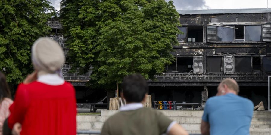 Anwohnerinnen und Anwohner machen sich ein Bild von den durch den Brand verursachten Schäden am Schulhaus. (Archivbild)