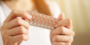 Person hält Packung mit Pillen in den Händen