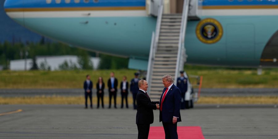 Trump und Putin begrüssen sich mit einem Handschlag.