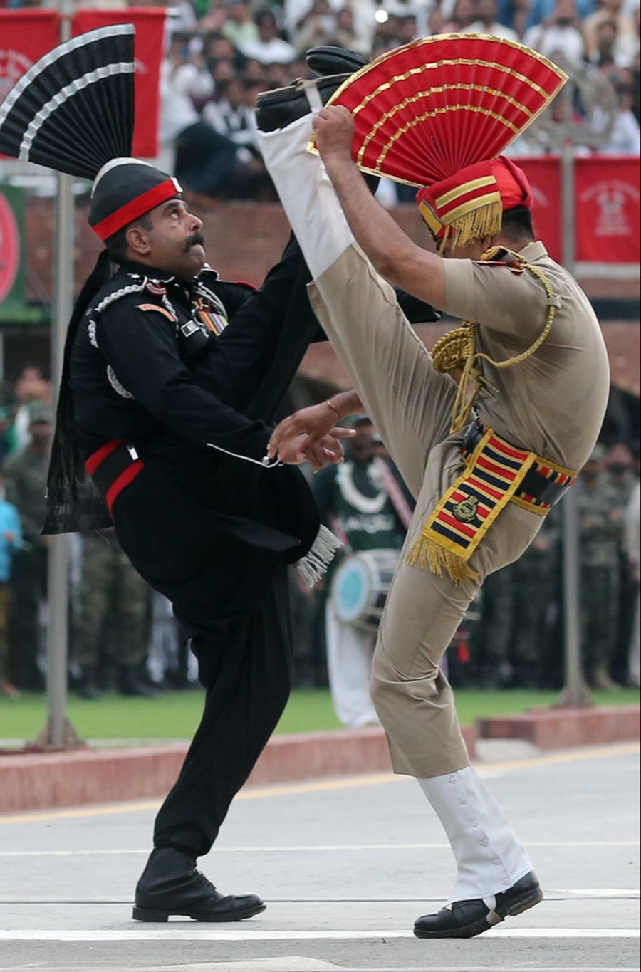 Das Ritual hat sich zu einem erbitterten Wettstreit zwischen den dunkel gekleideten Soldaten Pakistans und den beige gekleideten Soldaten Indiens entwickelt.