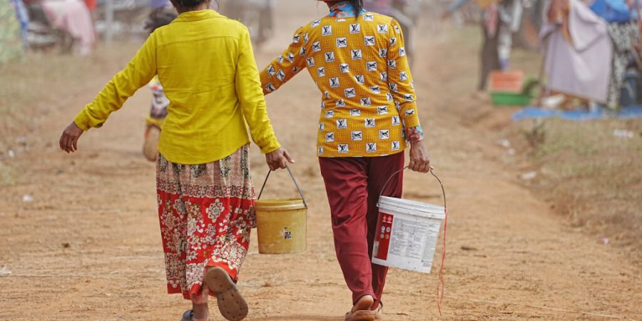 Evakuierte tragen Wasser, als sie in Chonkal Zuflucht suchen, nachdem sie aufgrund von Kämpfen zwischen Thailand und Kambodscha um Gebietsansprüche geflohen sind. Foto: Heng Sinith/AP/dpa