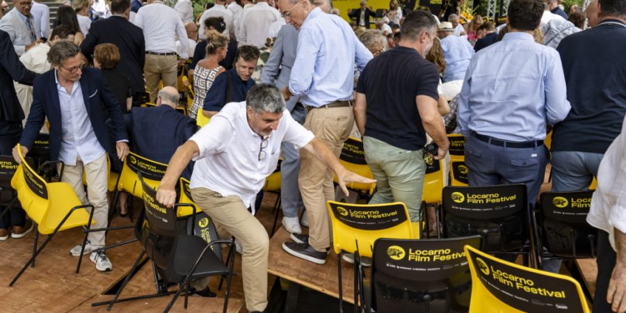Gäste stehen am Empfang des Locarno Film Festivals auf dem Monte Verità von ihren Stühlen auf, weil ein Teil derr Bühne nachgab.
