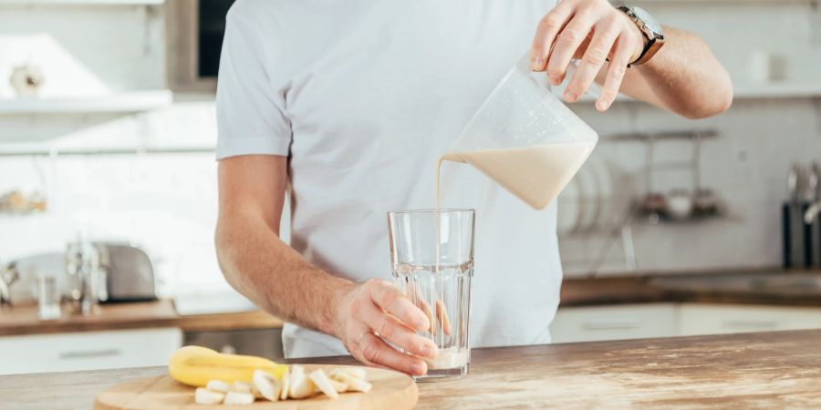 Mann schenkt sich Protein-Smoohie ein.