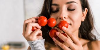 Frau riecht an Tomatenstrauch Küche