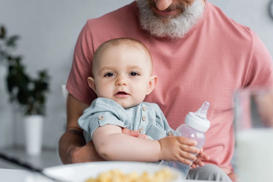 baby mit fläschchen in der hand