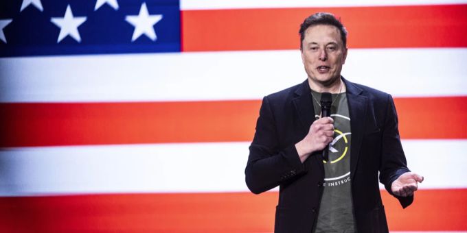 Elon Musk wanderte wohl illegal in die USA ein. musk vor us-flagge