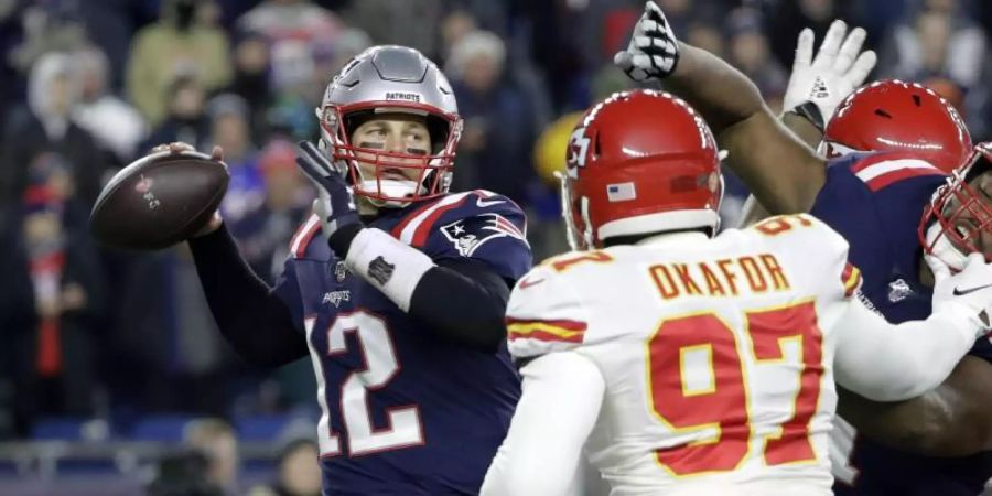 Quarterback Tom Brady von den Patriots (l) setzt zu einem Pass an, bedrängt von Kansas-Spieler Alex Okafor. Foto: Steven Senne/AP/dpa