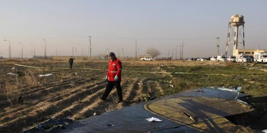 Eine Rettungskraft begutachtet ein grösseres Trümmerteil der ukrainischen Passagiermaschine. Foto: Ebrahim Noroozi/AP/dpa