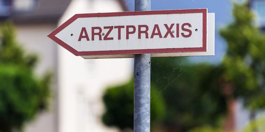 Ein Schild weist den Weg zu einer Arztpraxis.