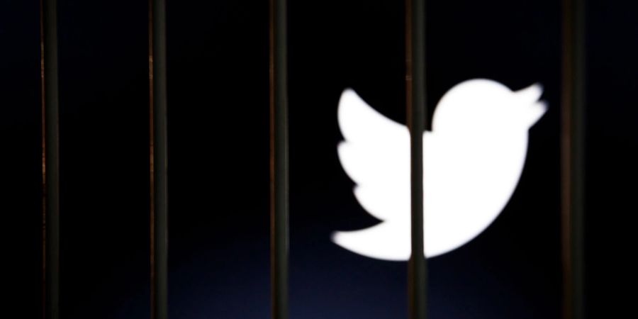 Das Twitter-Logo auf einem Bildschirm hinter Gittern.