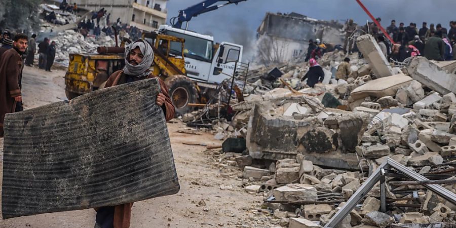 Rettungskräfte und Zivilisten suchen nach Menschen in den Trümmern eines zerstörten Gebäudes. Foto: Anas Alkharboutli/dpa