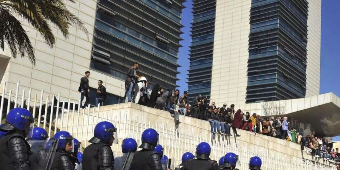 Polizisten sind in Algier aufgezogen und beobachten Demonstranten, die gegen eine erneute Kandidatur des algerischen Präsidenten Bouteflika protestieren. Foto: Fateh Guidoum/AP Polizisten sind in Algier aufgezogen und beobachten Demonstranten, die gegen eine erneute Kandidatur des algerischen Präsidenten Bouteflika protestieren. Foto: Fateh Guidoum/AP