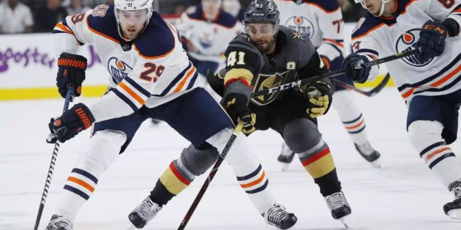 Oilsers-Spieler Leon Draisaitl (l) behauptet sich am Puck gegen Pierre-Edouard Bellemare (M) von den Vegas Golden Knights. Foto: John Locher/AP/dpa