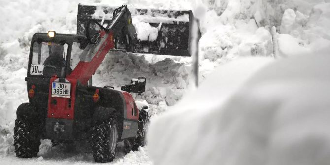 Ein Bagger befreit eine Strasse von den Schneemassen.