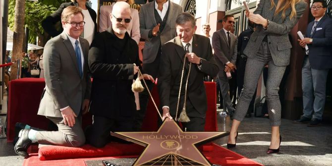 Ryan Murphy (m.) kniet auf dem roten Teppich während er seien Stern in den Boden von Hollywoods «Walk of Fame» einlässt.