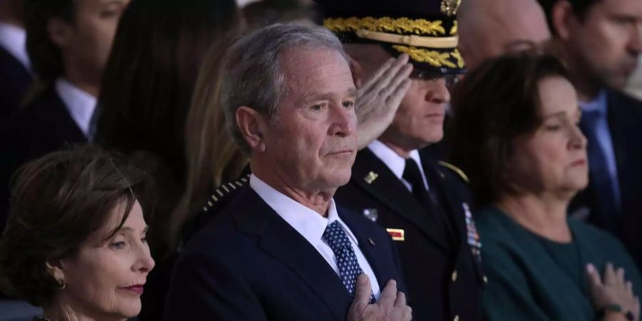 George W. Bush hält an der Beerdigung seines Vaters die Hand an seine Brust.