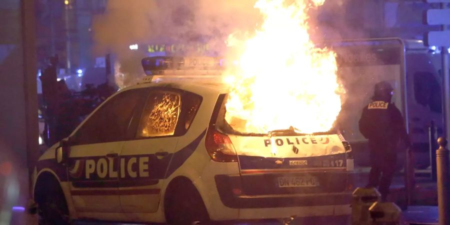 Ein Polizeiauto brennt nach Zusammenstössen zwischen Polizei und Demonstranten.