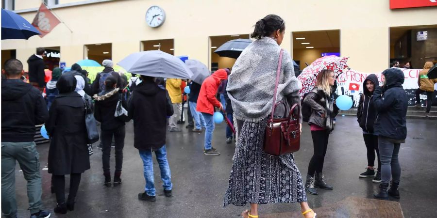 Menschen im Tessin schützen sich vor dem Regen mit Schirmen.