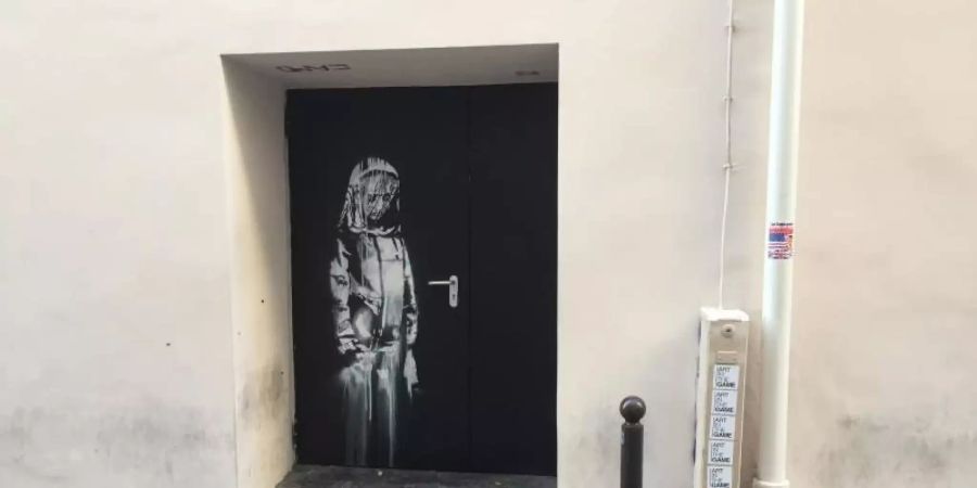 Auf einer Tür beim Pariser Musikclub "Bataclan" ist ein Wandbild zu sehen, das dem britischen Street-Art-Künstler Banksy zugerechnet wird. Foto: Sebastian Kunigkeit/dpa