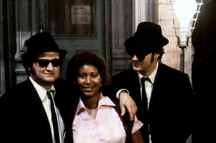 Diverse Berühmtheiten aus dem Unterhaltungsgeschäft geben sich für die «Blues Brothers» ein Stelldichein. Hier posiert die 2018 verstorbene Sängerin Aretha Franklin mit den Hauptdarstellern.