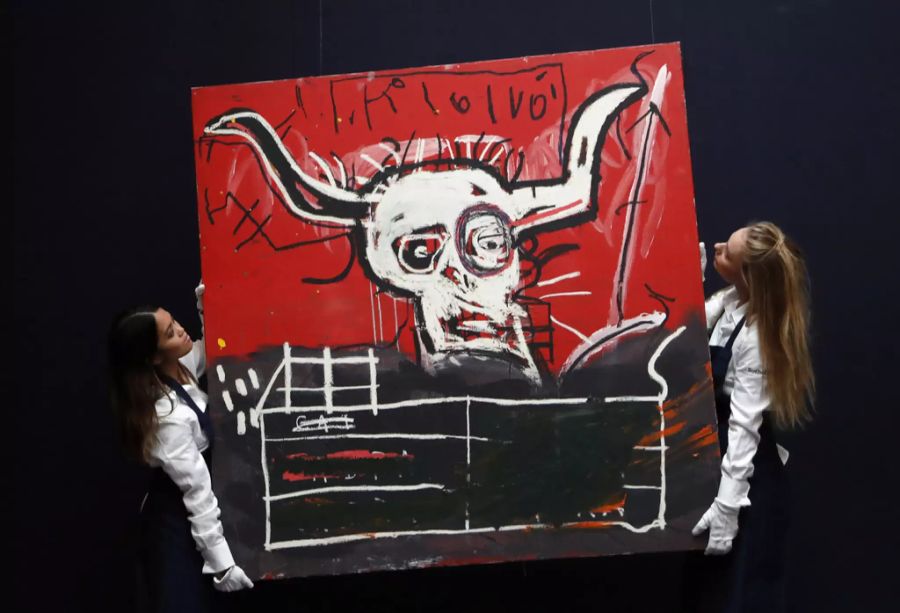 Zwei Angestellte des Auktionshauses Sotheby's tragen ein Gemälde von Jean-Michel Basquiat.