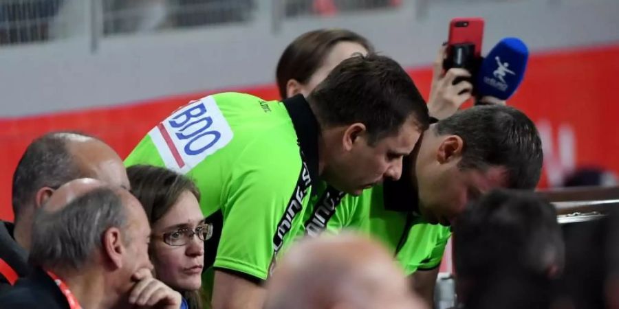 Zwei Schiedsrichter schauen beim Handball auf einen Bildschirm beim Videobeweis. Foto: Monika Skolimowska/zb/dpa