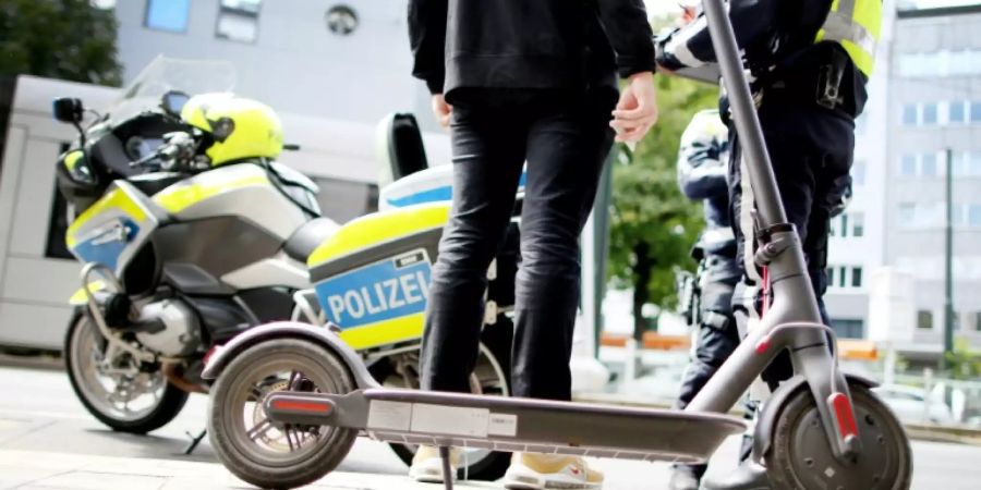 Polizisten kontrollieren einen E-Scooter-Fahrer