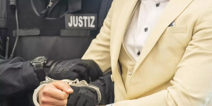 Der Angeklagte wird von einem Justizbeamten in den Gerichtssaal geführt. Foto: Matthias Rietschel