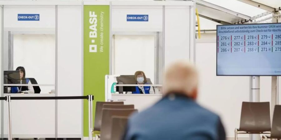 Ein geimpfter Mitarbeiter sitzt im BASF-Impfzentrum im Wartebereich, in dem mögliche Nebenwirkungen der Corona-Impfung beobachtet werden. Foto: Uwe Anspach/dpa