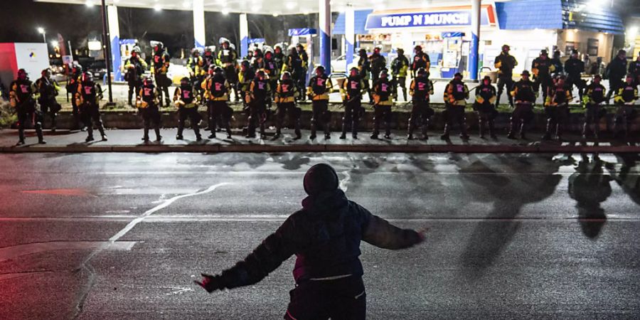 Ein Demonstrant steht während eines Protests gegen Polizeigewalt vor Polizisten. Knapp elf Monate nach dem Tod von George Floyd in Minnesota ist im selben US-Bundesstaat erneut ein Schwarzer von der Polizei getötet worden. Foto: John Minchillo/AP/dpa