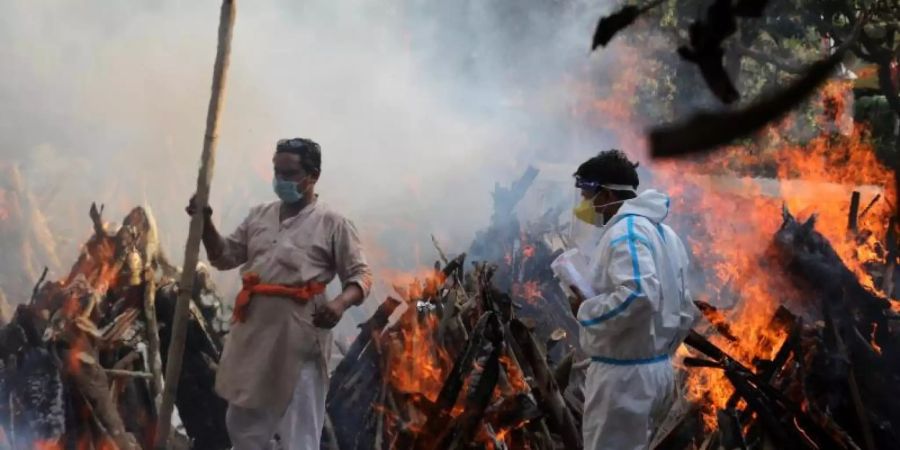 Neu-Delhi: Angehörige neben brennenden Scheiterhaufen von Opfern, die an den Folgen einer Corona-Infektion gestorben sind. Foto: Naveen Sharma/SOPA/ZUMA/dpa