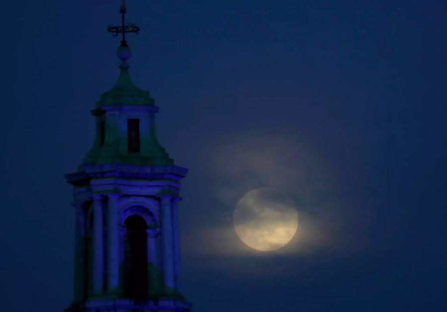 Der Mond geht durch die Wolken über der County Hall in London auf.