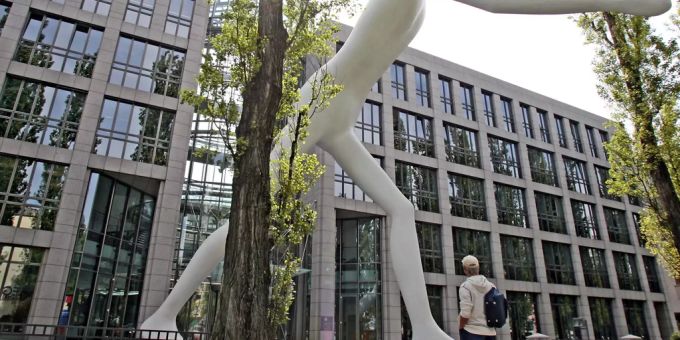 Ein Mann steht vor der Statue «Walking Man» des amerikanischen Künstlers Jonathan Borofsky vor der Firmenzentrale der Rückversicherung Münchener Rück in München im Jahr 2007. Münchener Rück