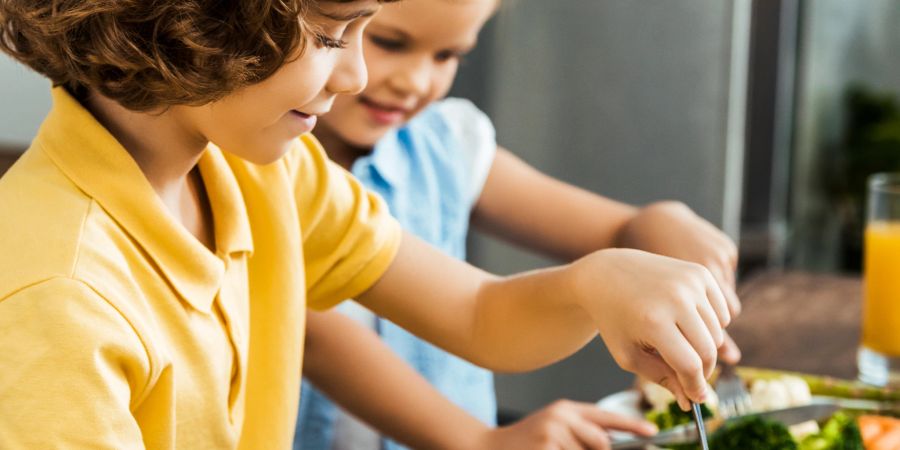 junge und mädchen essen brokkoli