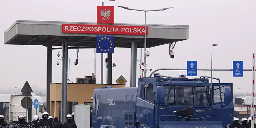 Polnische Sicherheitskräfte und ein Wasserwerfer stehen hinter dem gesperrten Grenzübergang Brusgi (Belarus) und Kuznica (Polen). Foto: Ulf Mauder/dpa