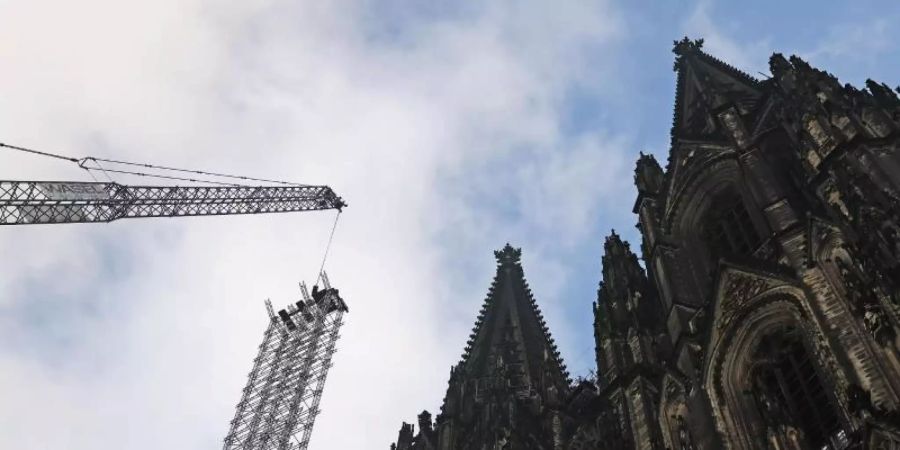 Ein Teil des Baugerüstes wird vor dem Dom heruntergelassen. Foto: Oliver Berg/dpa