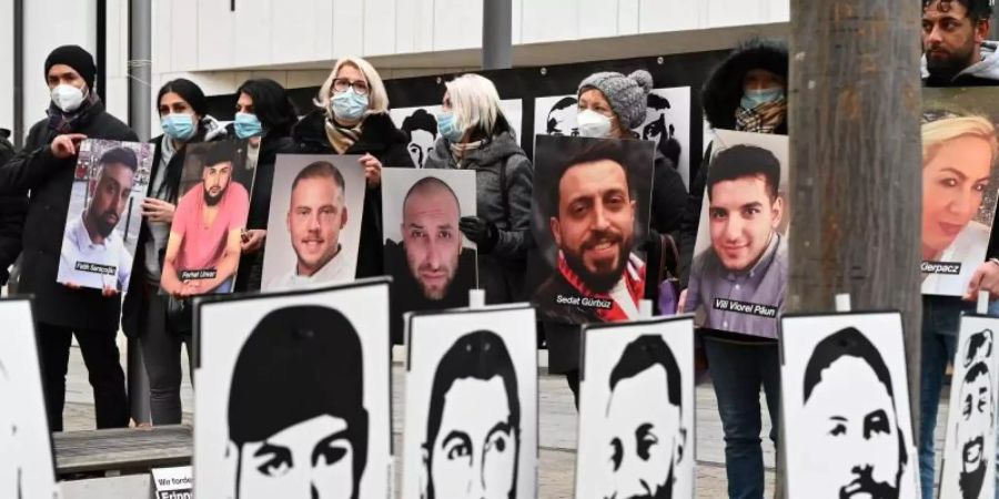 Angehörige der Opfer des rassistischen Anschlags von Hanau 2020 halten bei einer Mahnwache vor dem hessischen Landtag Fotos der Opfer. Foto: Arne Dedert/dpa