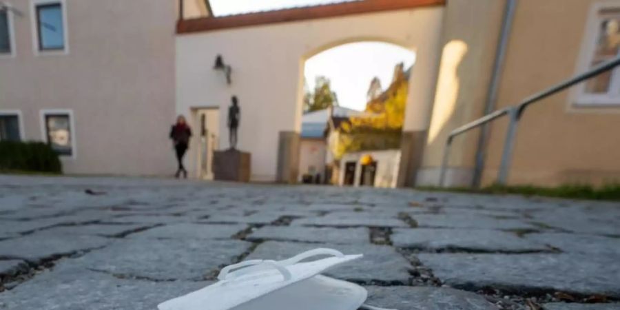 Eine FFP2-Maske liegt auf einem Weg in der Innenstadt von Pfarrkirchen in Bayern. Foto: Armin Weigel/dpa