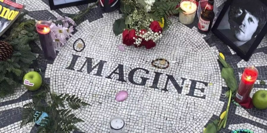 Fotos, Blumen und Kerzen an der Gedenkstätte «Strawberry Fields» in New Yorks Central Park. Foto: Mark Lennihan/AP/dpa