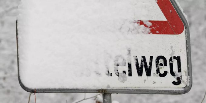 Verschneite Hinweistafel für den Schlittelweg.