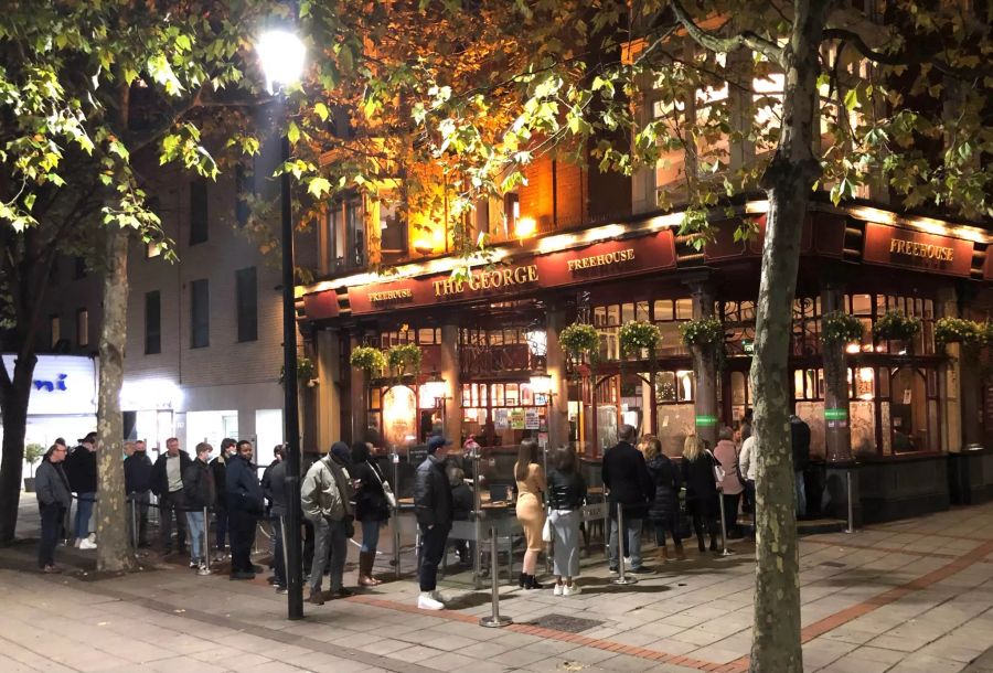 Die Menschen warten vor dem Pub The George in einer Schlange. Das Bild wurde am Abend vor dem zweiten Lockdown aufgenommen.