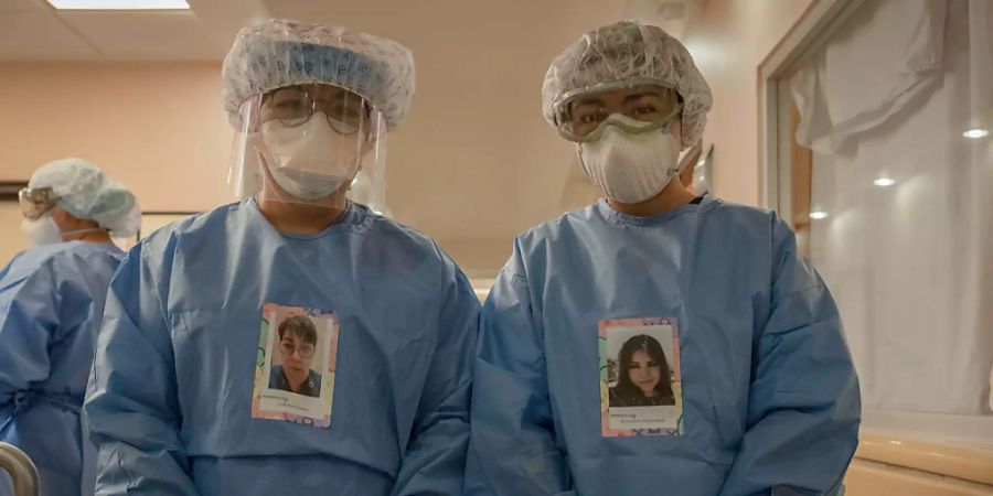 Dr. Lilian Revelez (l) und Maria Fernanda Negrete (r) stehen in Schutzkleidungen mit ihren Porträts vor der Intensivstation für Covid-19-Patienten in der Fachklinik für Lungen- und Atemwegserkrankungen INER. Foto: Jacky Muniello/dpa