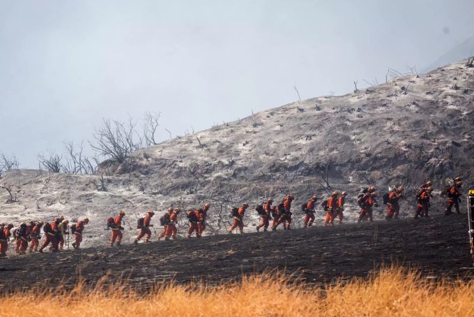 Feuerwehrleute vor einer verbrannten Landschaft in Kalifornien. waldbrand