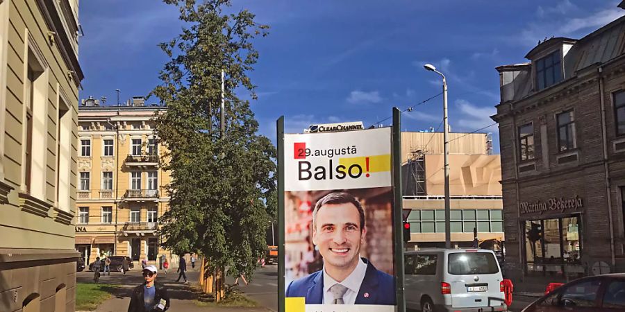 Ein Wahlplakat der gemeinsam antretenden liberalen Parteien Für die Entwicklung / Dafür! und Progressive mit einem Porträt ihres Bürgermeisterkandidaten Martins Stakis steht in der Hauptstadt. Foto: Alexander Welscher/dpa - ACHTUNG: Nur zur redaktionellen Verwendung im Zusammenhang mit einer Berichterstattung über Kommunalwahl